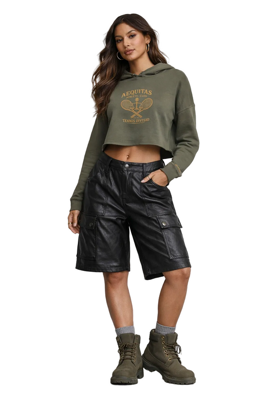 Woman wearing a green hoodie and black leather shorts against a gray background