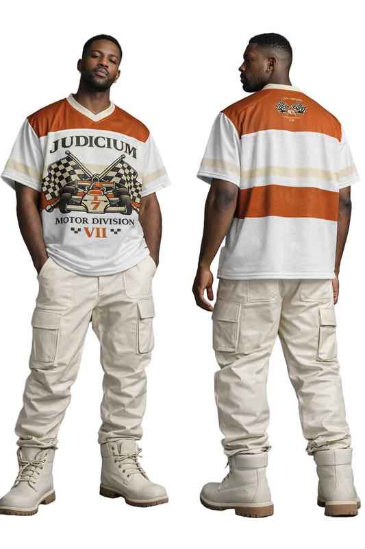 Man wearing a 'Judicium Motor Division VII' shirt and beige cargo pants, standing against a gray background.