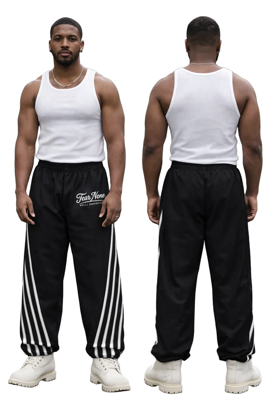 Person wearing a white tank top and black pants with white stripes, standing against a green hedge.