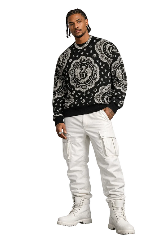 Man wearing a black patterned sweater, white pants, and white boots on a gray background