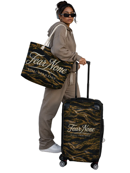 Person holding a 'Fear None' bag and suitcase at an airport.