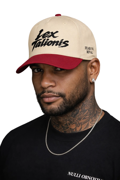 Man wearing a beige and red cap with text, against a gray background