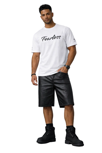 Man wearing a white t-shirt with 'Fearless' text, black leather shorts, and black boots against a gray background.