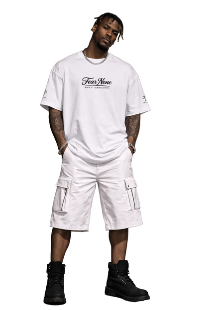 Man wearing a white t-shirt and cargo shorts with 'Fear None' text, standing in an urban setting.
