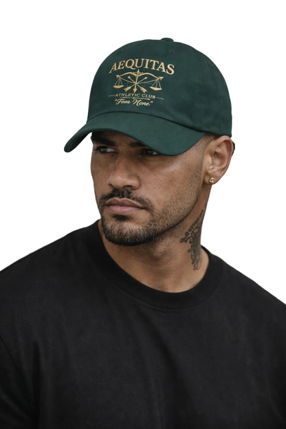 Man wearing a green cap with 'AEQUITAS' branding against a neutral background