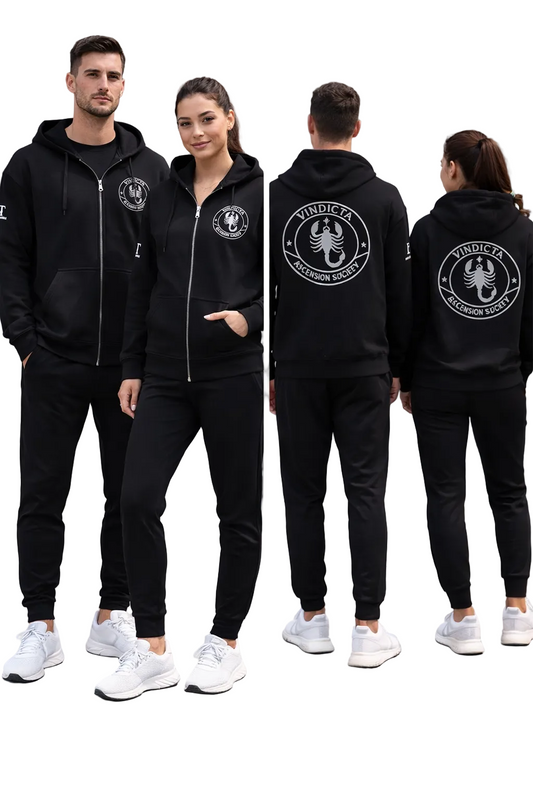 Two people wearing black tracksuits with a logo on the back, standing against a gray wall.