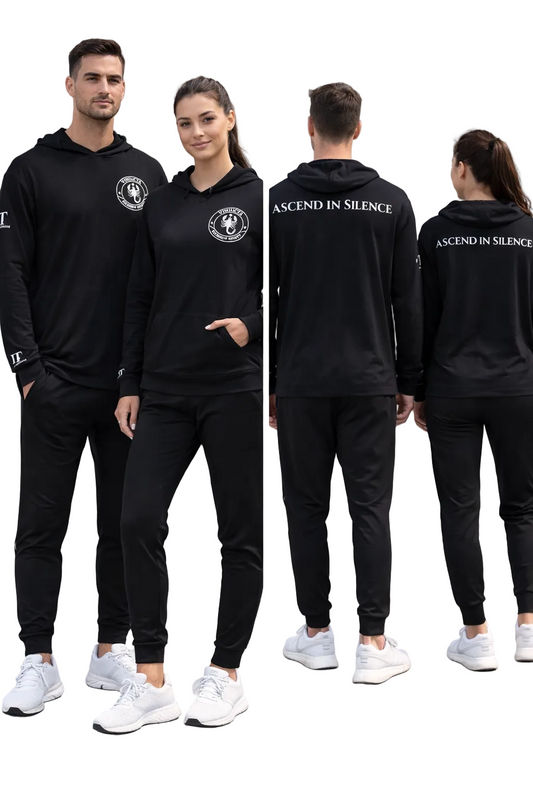 Two people wearing black tracksuits with 'Ascend in Silence' text, standing on a concrete surface.