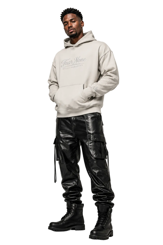 A man modeling a light beige hoodie with 'Fear and Loathing in Las Vegas' printed on the chest, paired with black cargo pants and black combat boots, against a light gray studio background.