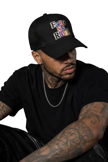 A man wearing a black trucker hat with the embroidered text 'Fear and Loathing in Las Vegas' in a multicolor retro font, paired with a black t-shirt and silver chain necklace.