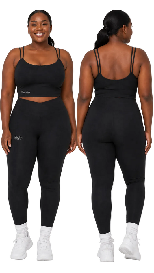 A plus-size model is shown from the front and back wearing a matching black activewear set consisting of a sports bra and leggings, paired with white sneakers against a light gray studio background.