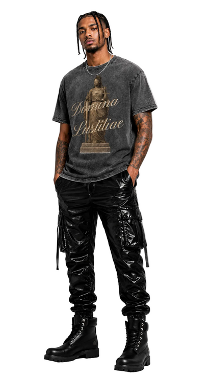Person wearing a dark gray t-shirt with text and graphics, black pants, and black boots on a light gray background